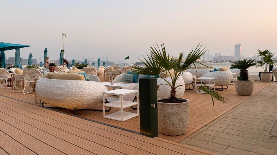 a deck with a lot of white furniture and a blue umbrella