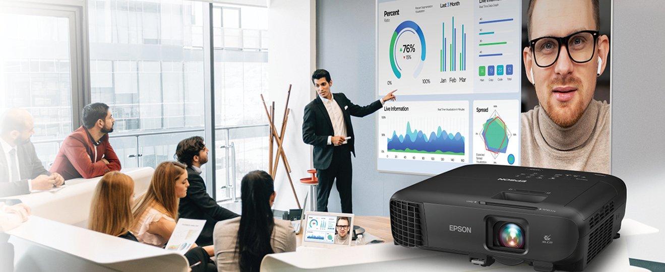 a group of people sitting around a conference table with a projector