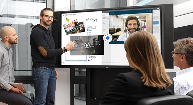 a group of people sitting around a large screen watching a presentation