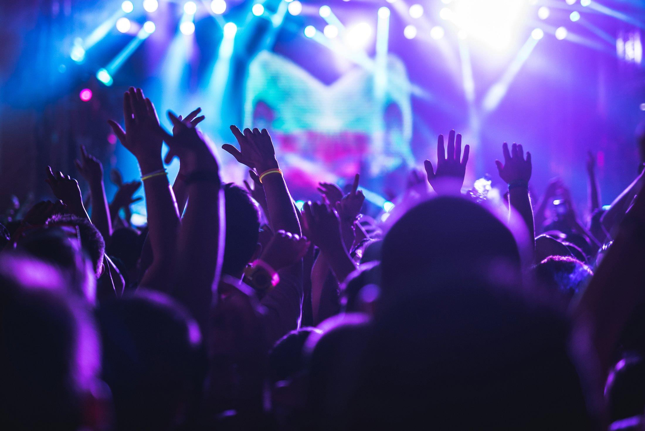 a crowd of people at a concert with their hands up