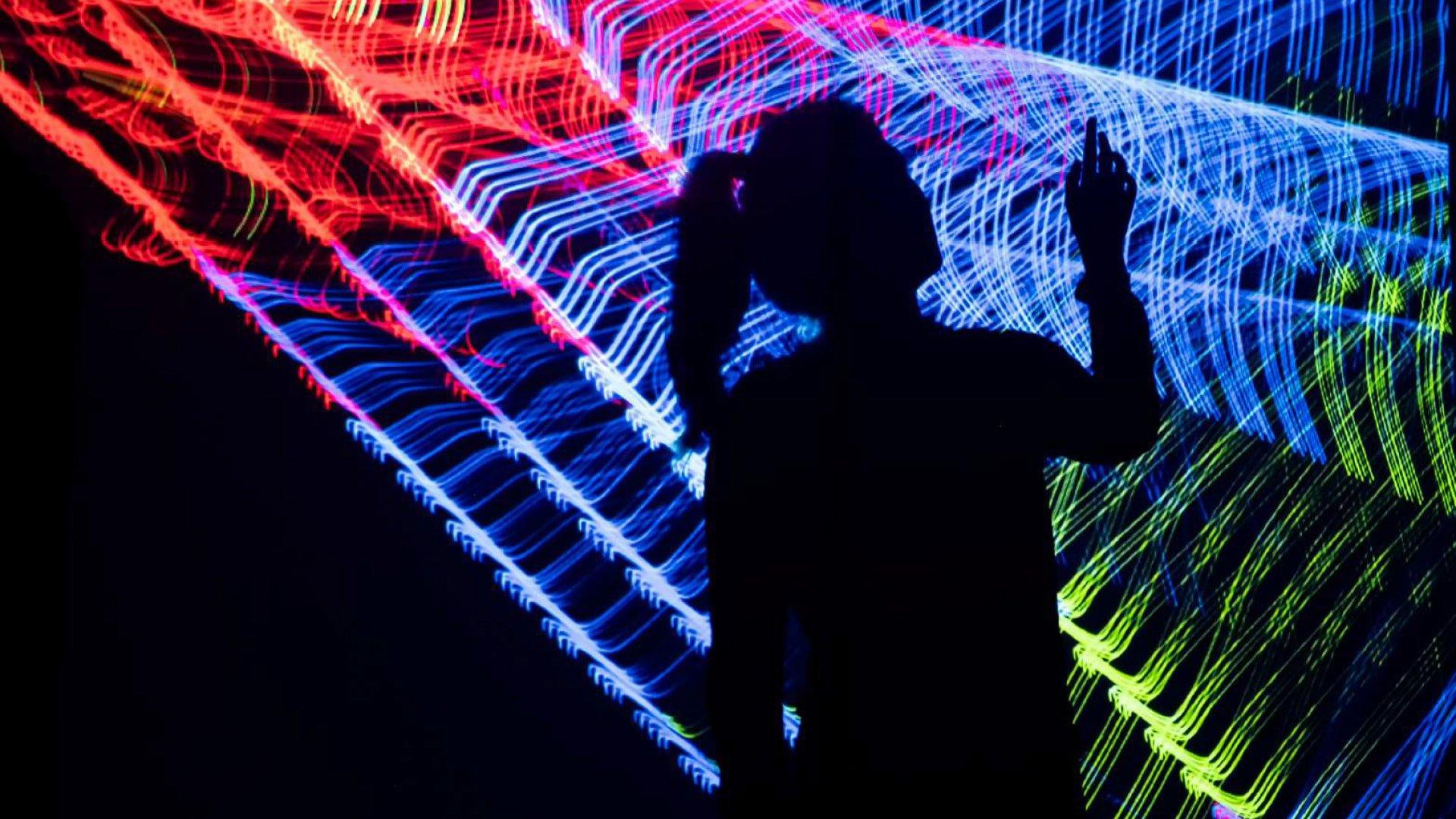 a person is silhouetted against a colorful light display