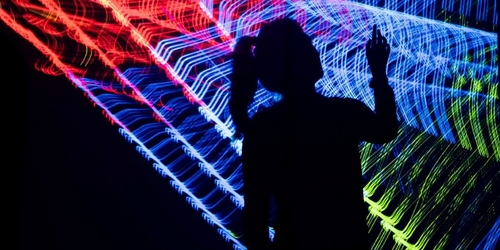 a person is silhouetted against a colorful light display a person is silhouetted against a colorful light display