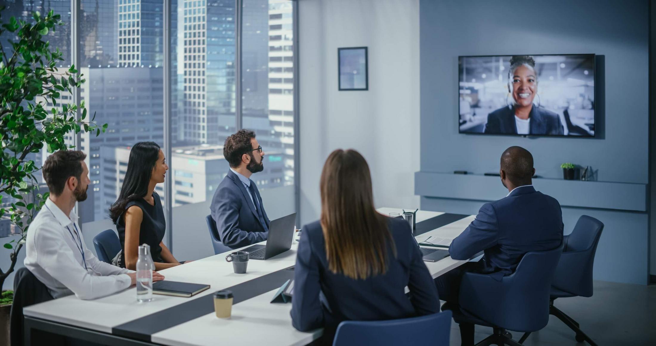 a group of people sitting at a table watching a video