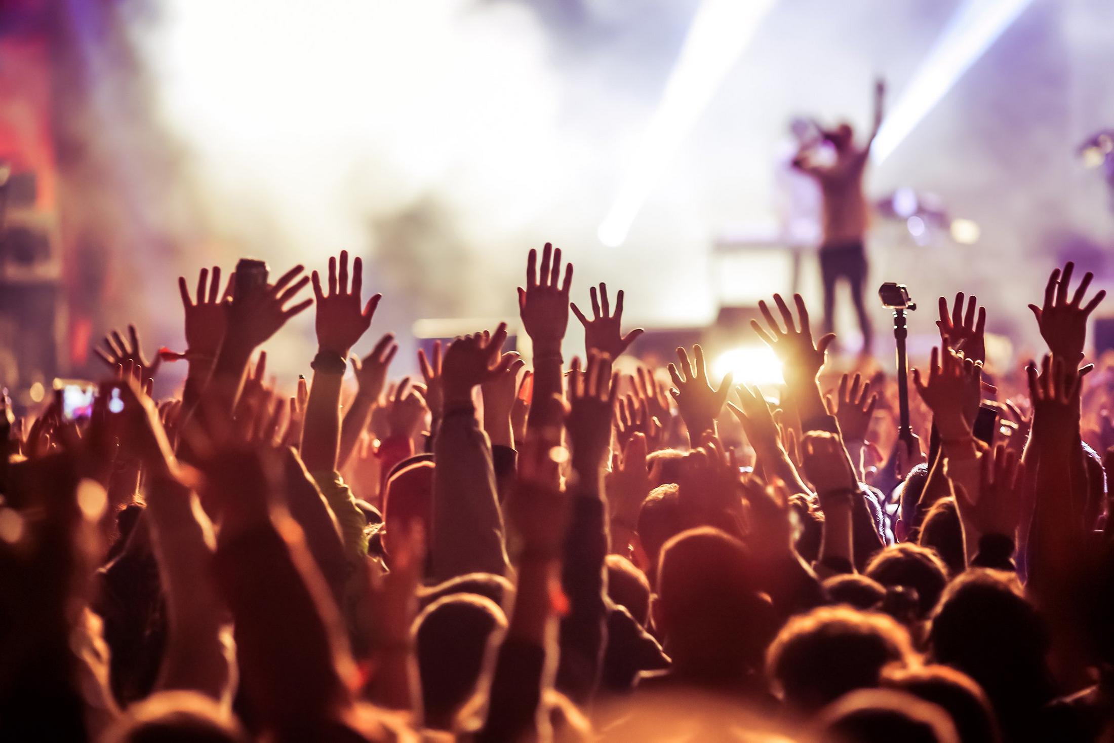 a crowd of people at a concert with their hands up