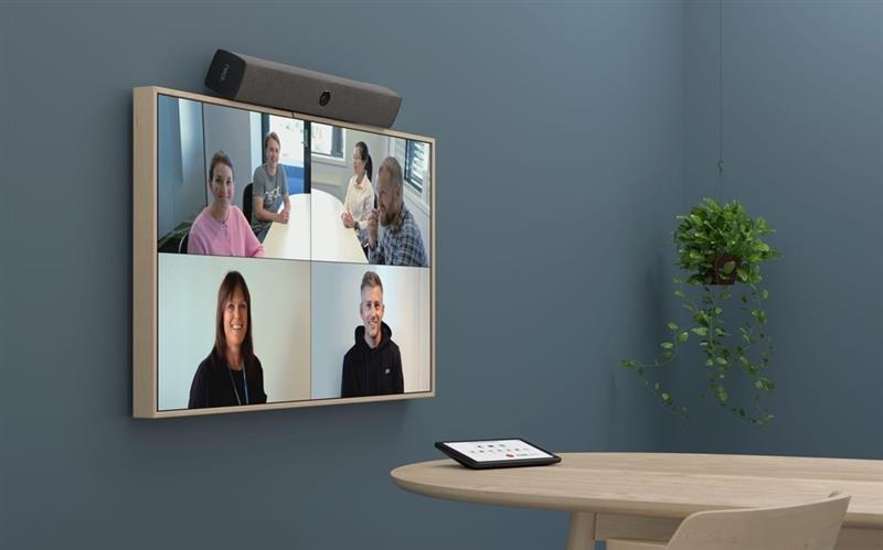 a wall mounted screen with a video of people talking in a room