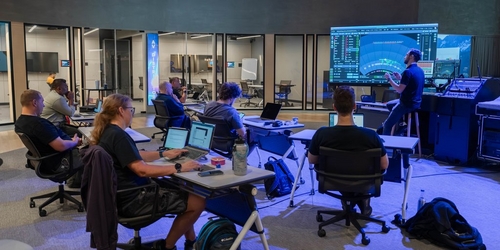 a group of people sitting at computers in a room a group of people sitting at computers in a room