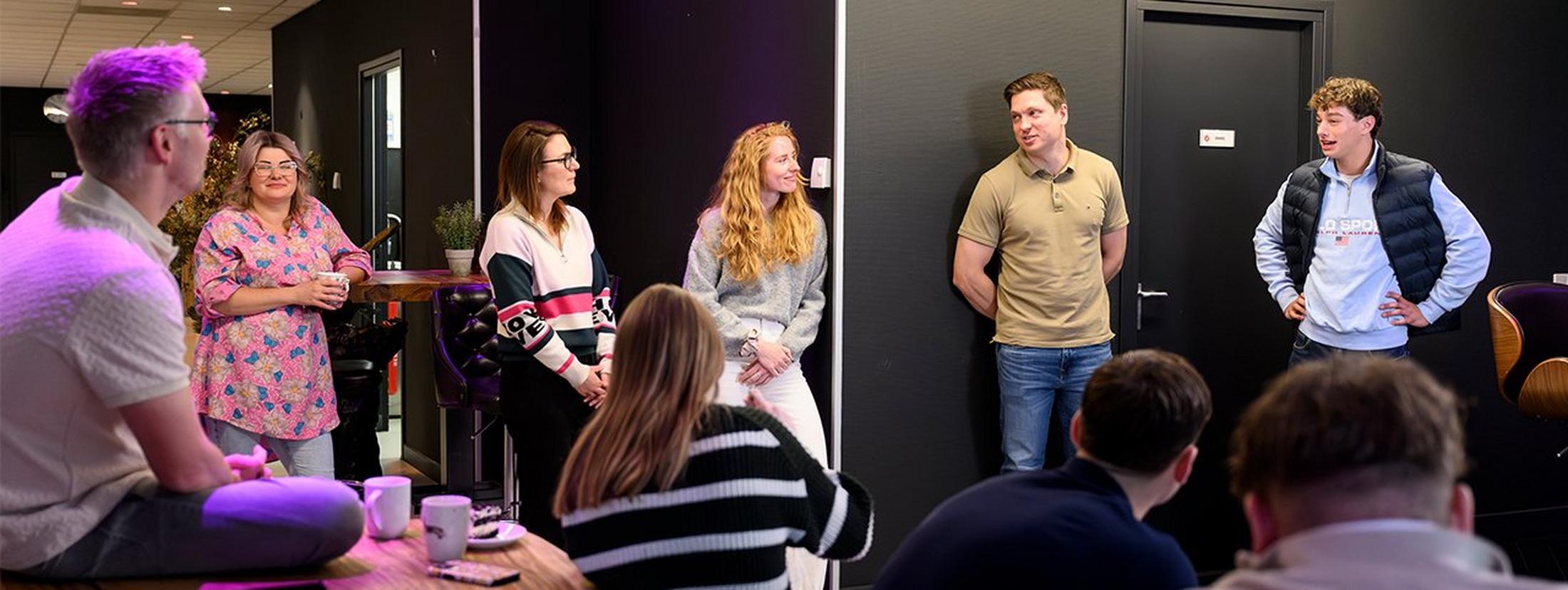 a group of people are sitting and standing in a room