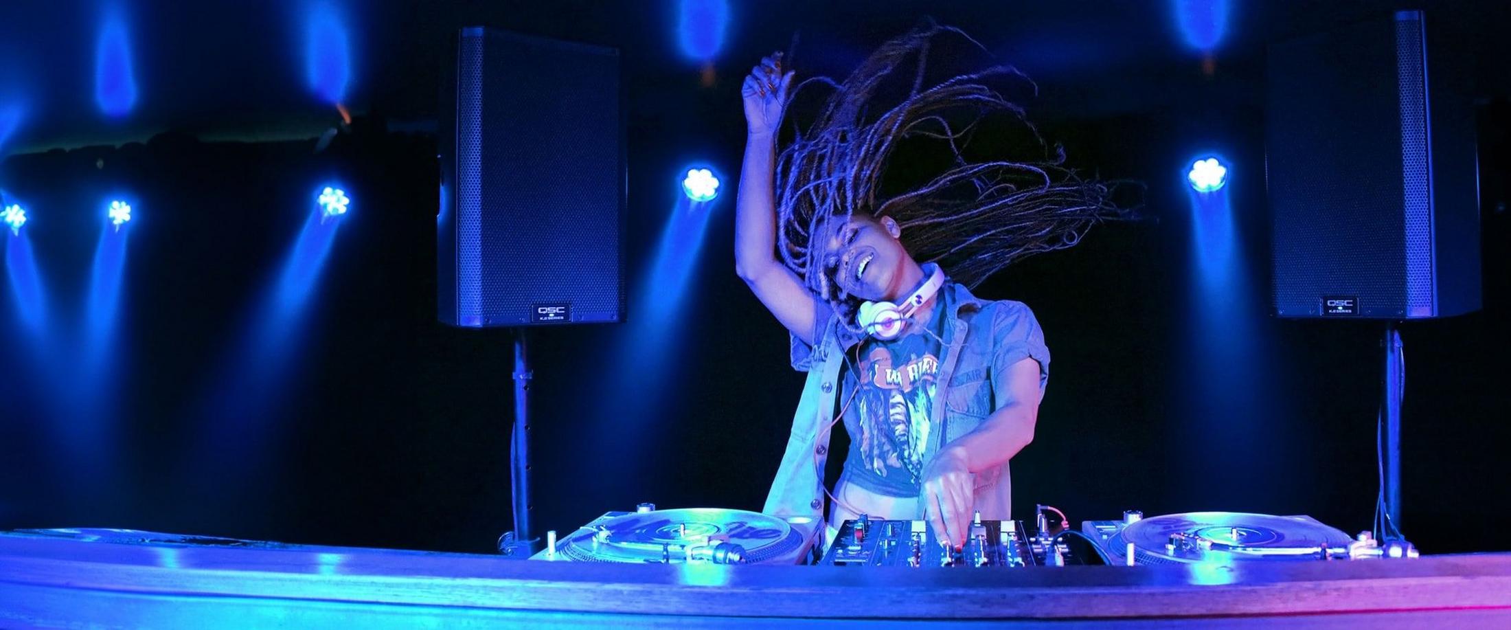 a dj spinning records on stage with lights behind him