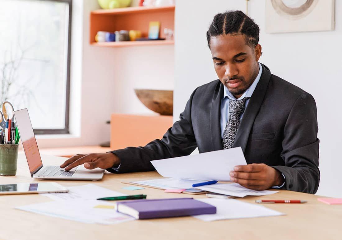 a man sitting at a desk with a laptop and paperwork