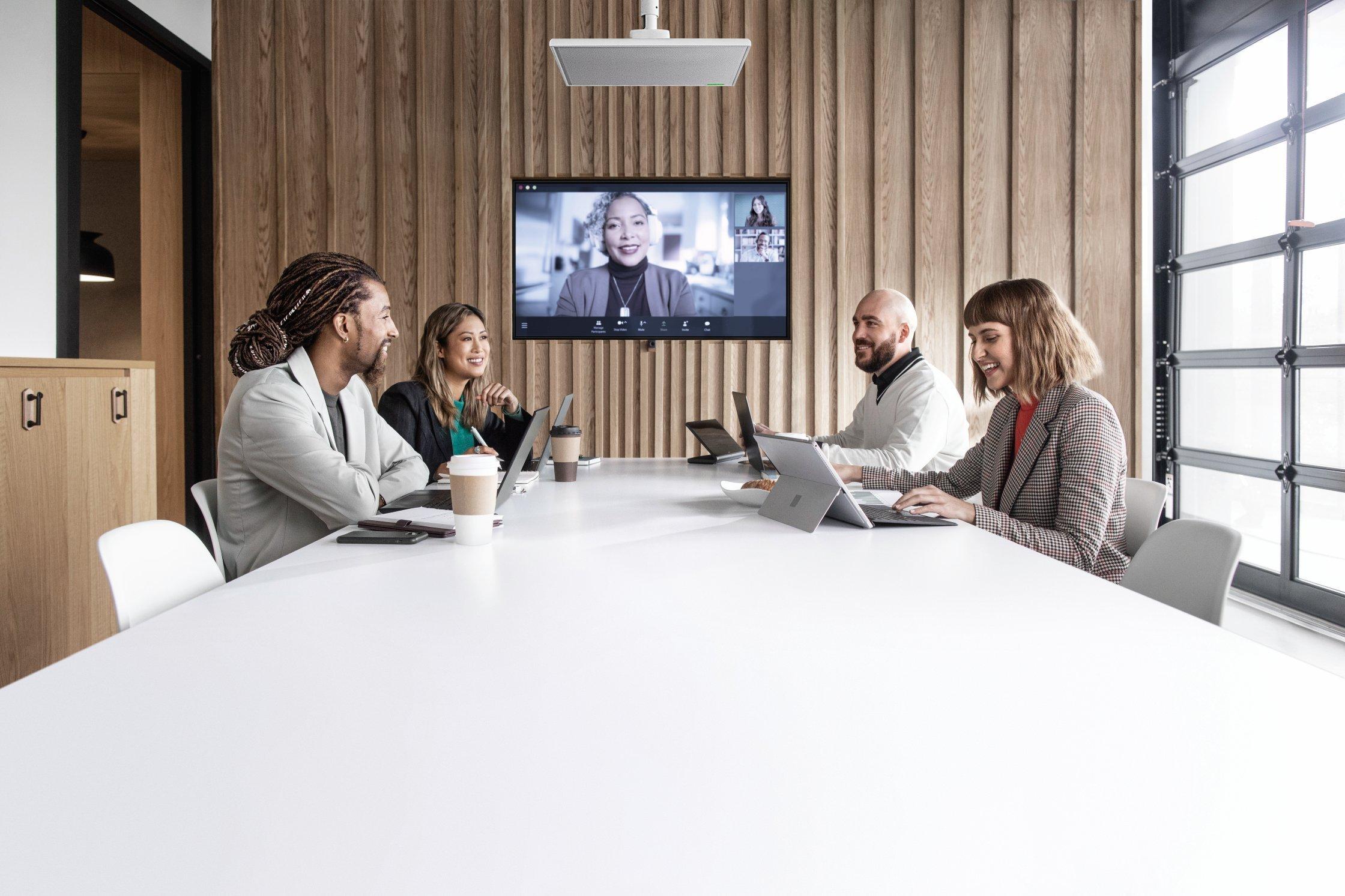 a group of people sitting around a table with laptops