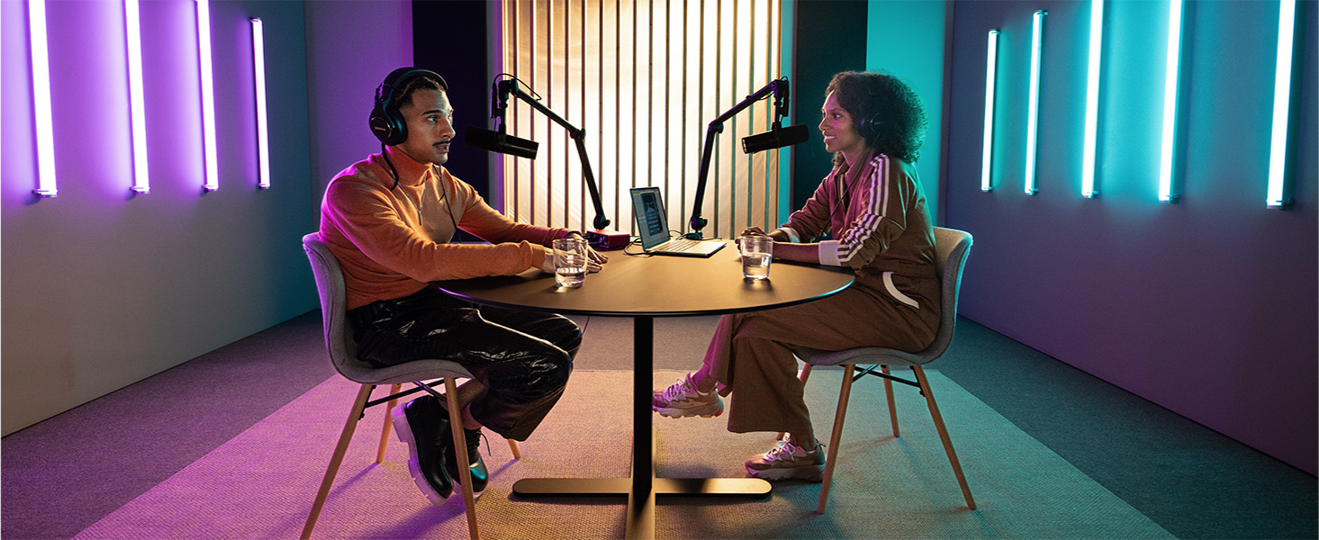 a man and woman sitting at a table with microphones