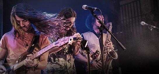 a group of musicians playing instruments on stage in front of a microphone