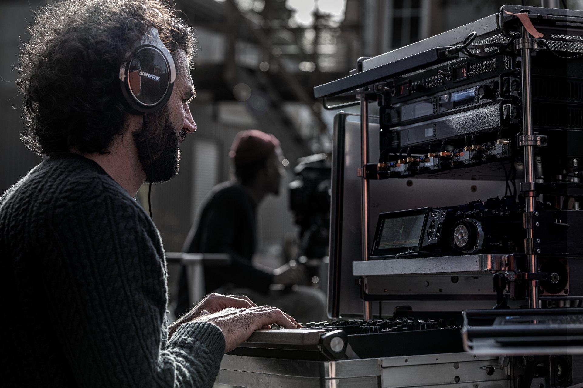 a man with headphones on working on a laptop computer