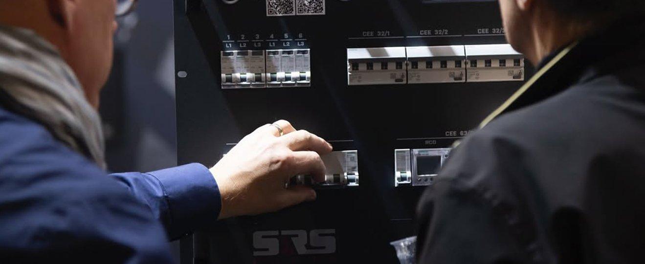 two men are looking at a control panel in a building