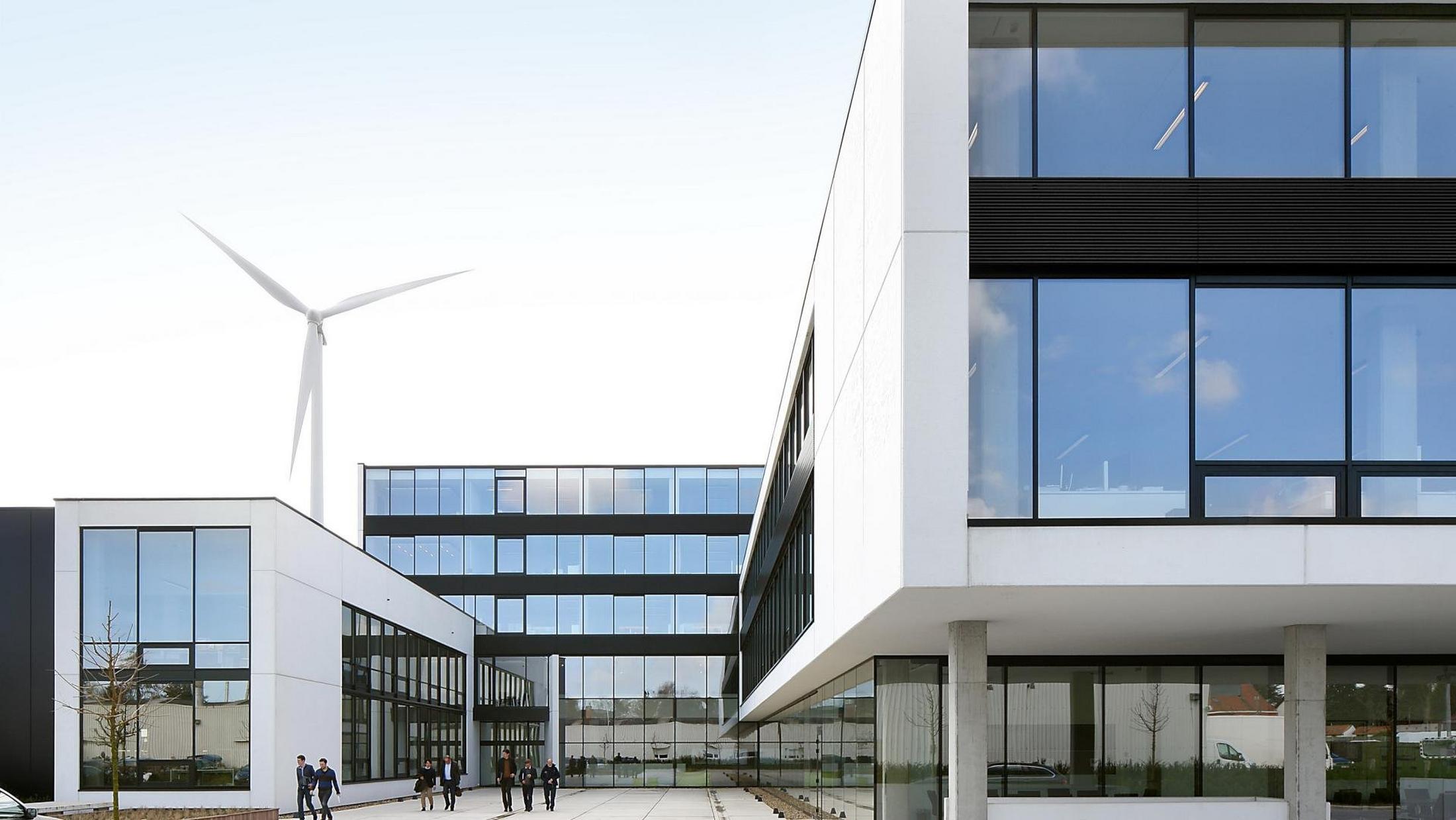 a building with a wind turbine on the roof and a couple of people walking by