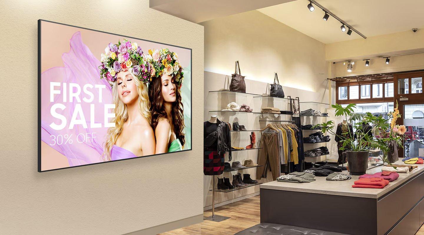 a large screen is mounted on the wall of a clothing store