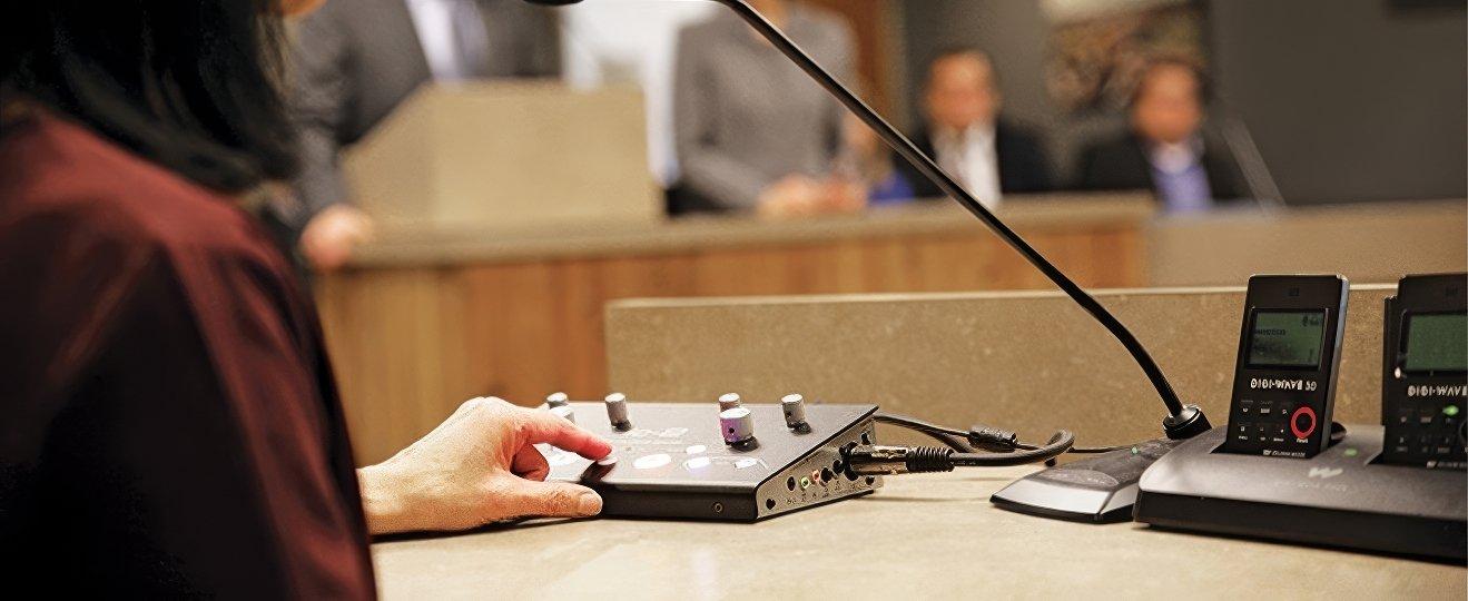 a woman sitting at a table with a microphone and a computer