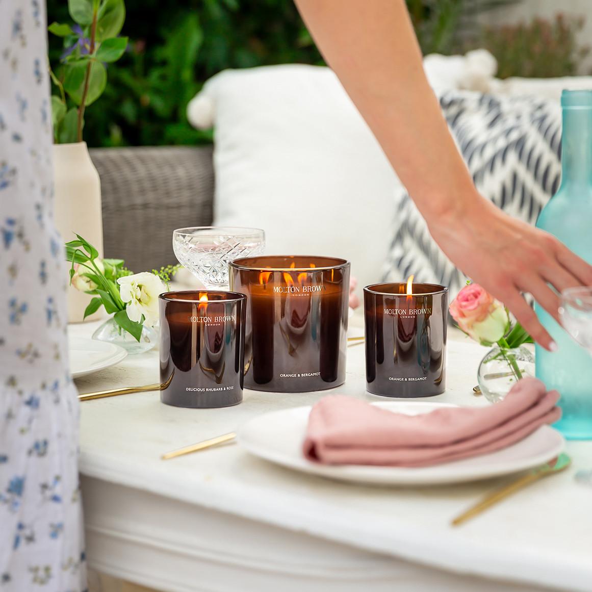 Molton Brown candles lit on an outdoor table.