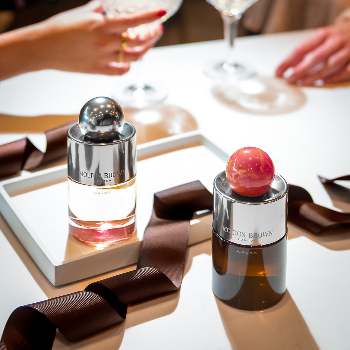 Molton Brown Rose Dunes fragrance bottles displayed on a tray with ribbon at a table setting.