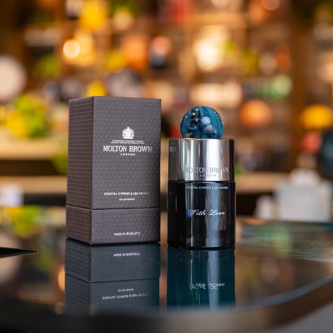 Molton Brown London Coastal Cypress & Sea Fennel Eau de Parfum bottle beside its textured grey box. 
