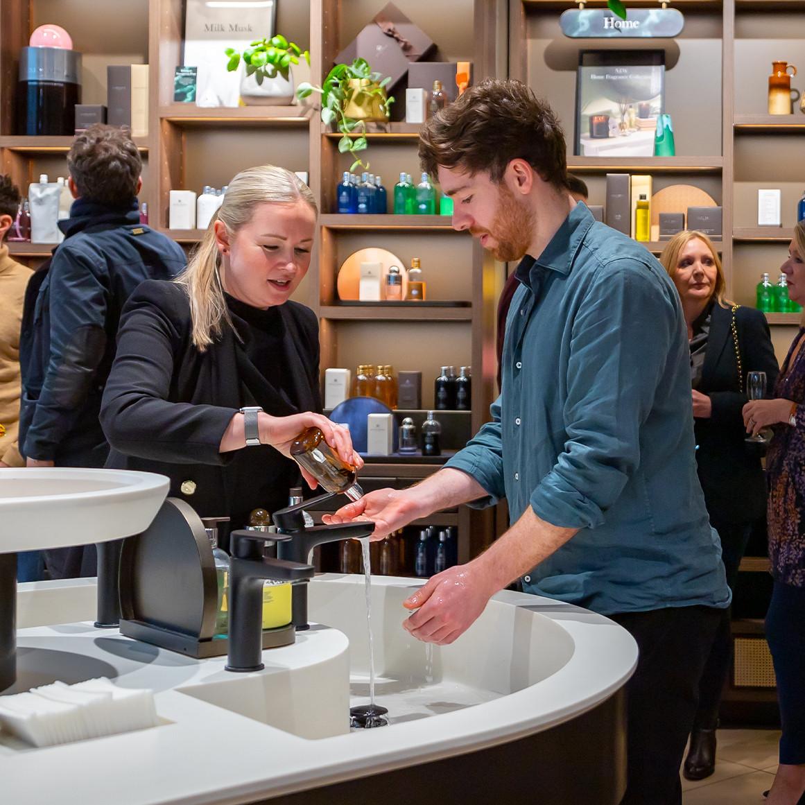 Shop assistant pouring Molton Brown hand wash for customer to try in store