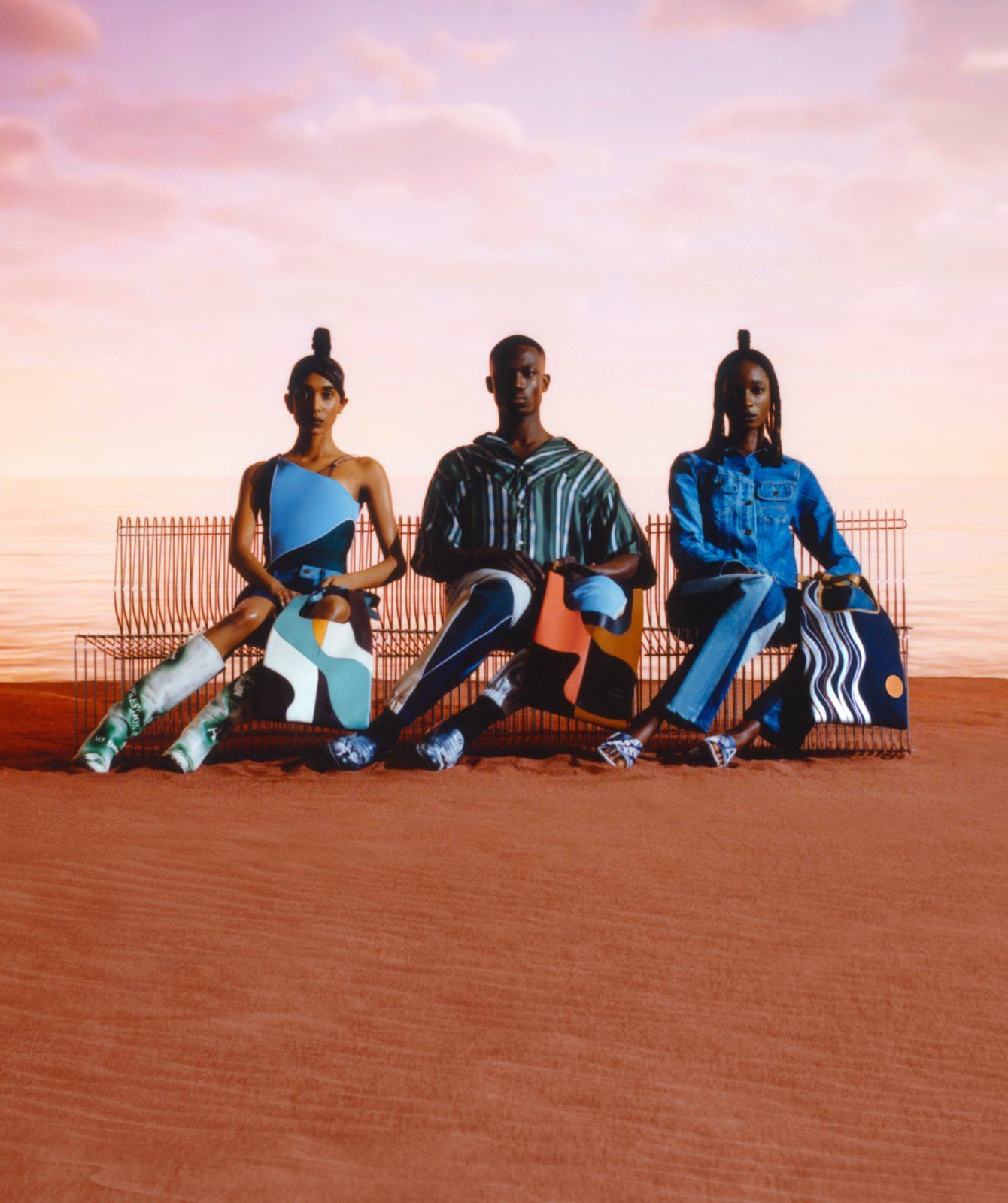 Three models sitting on a bench on the beach