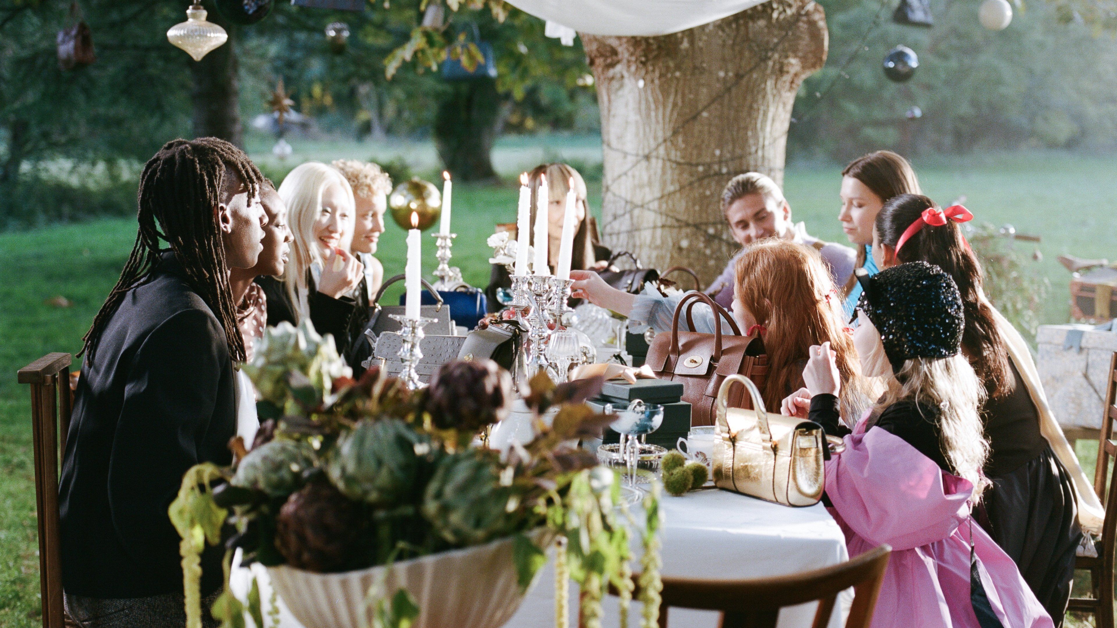 Group shot of people at table waving Mulberry handbags