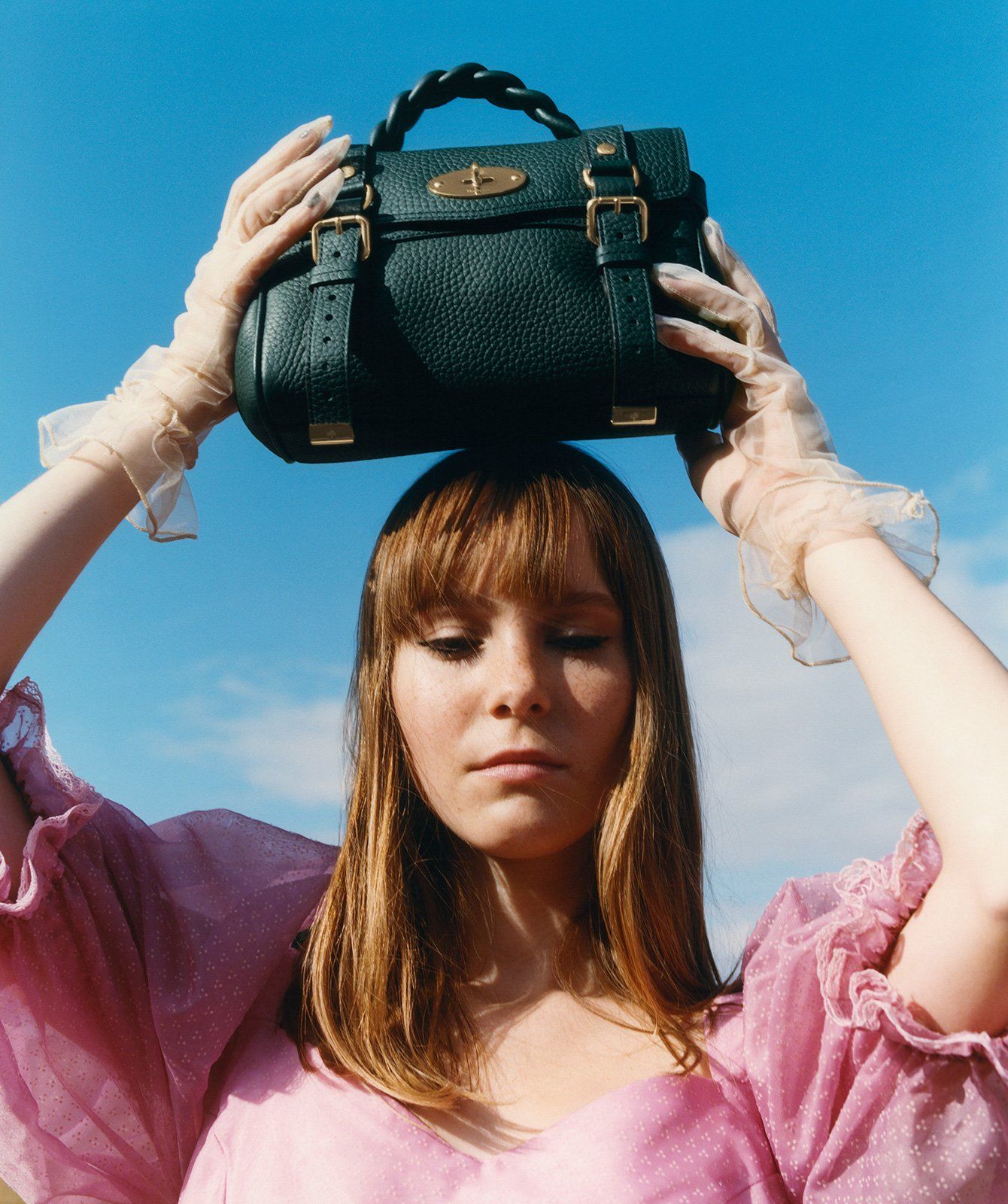 Model holding a Mini Alexa handbag in dark green leather