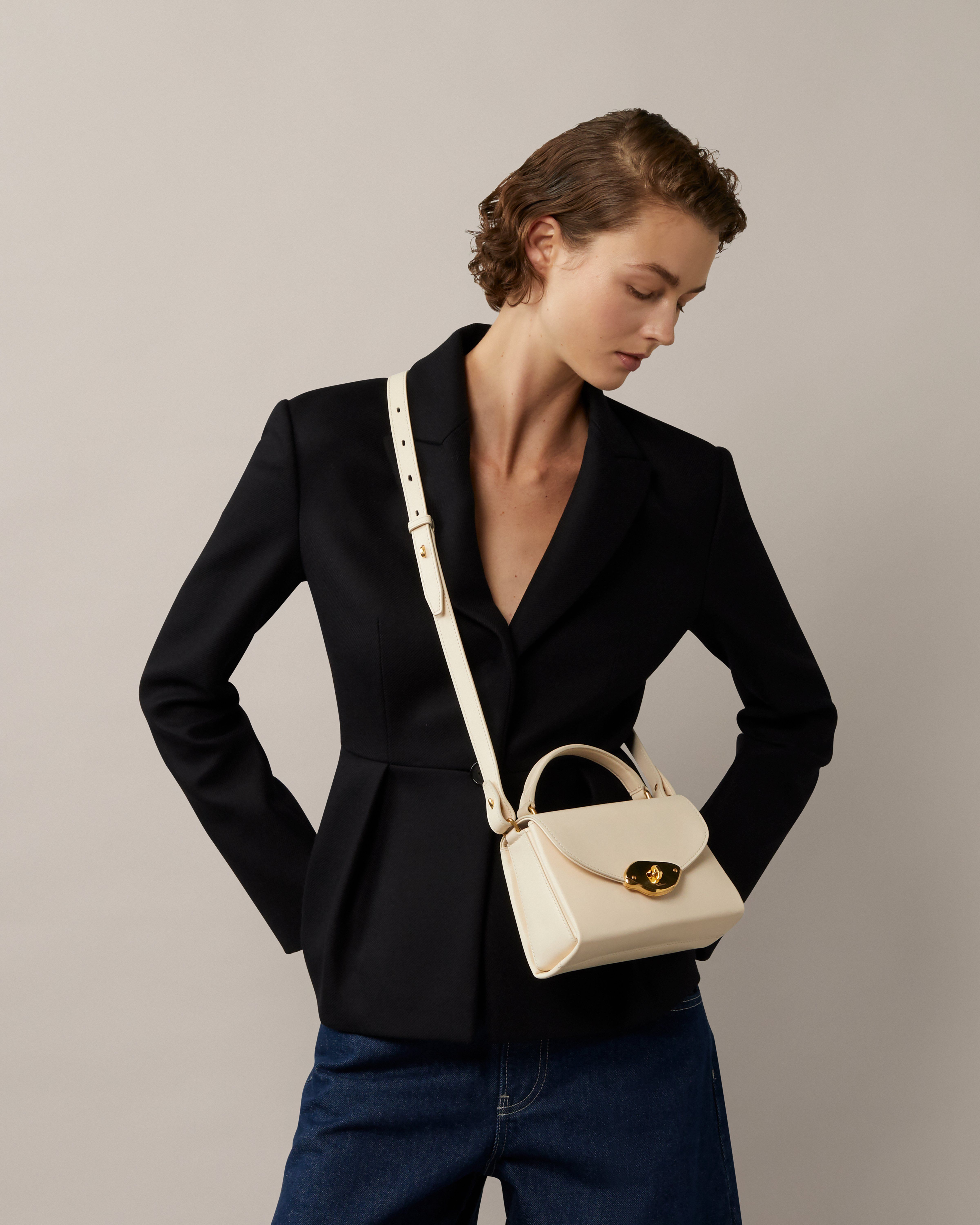 Model mit kleiner Lana Top Handle Tasche aus Hochglanzleder in Eggshell