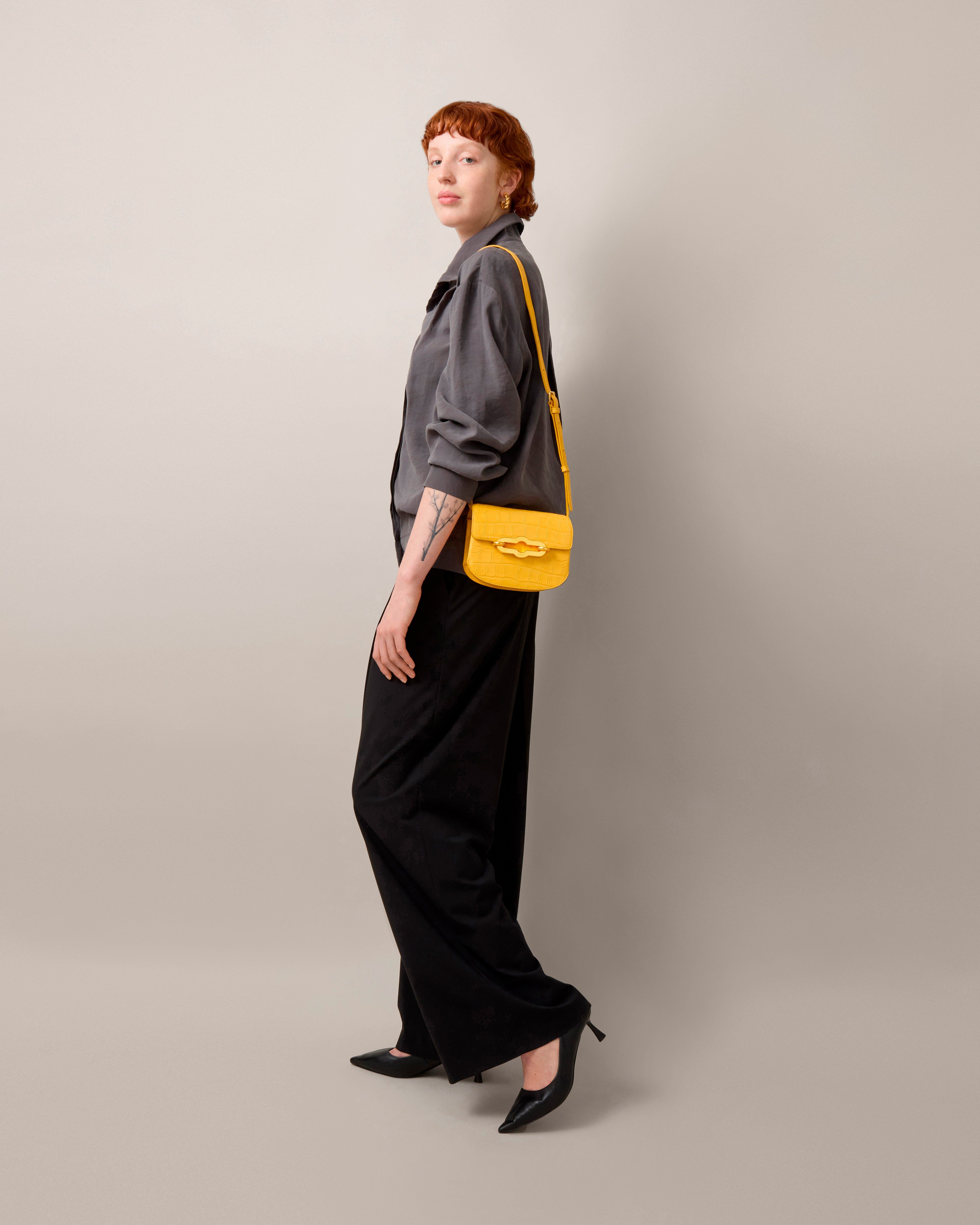 Model mit kleiner Pimlico Satchel Tasche aus mattem Leder mit Kroko-Prägung in Gelb