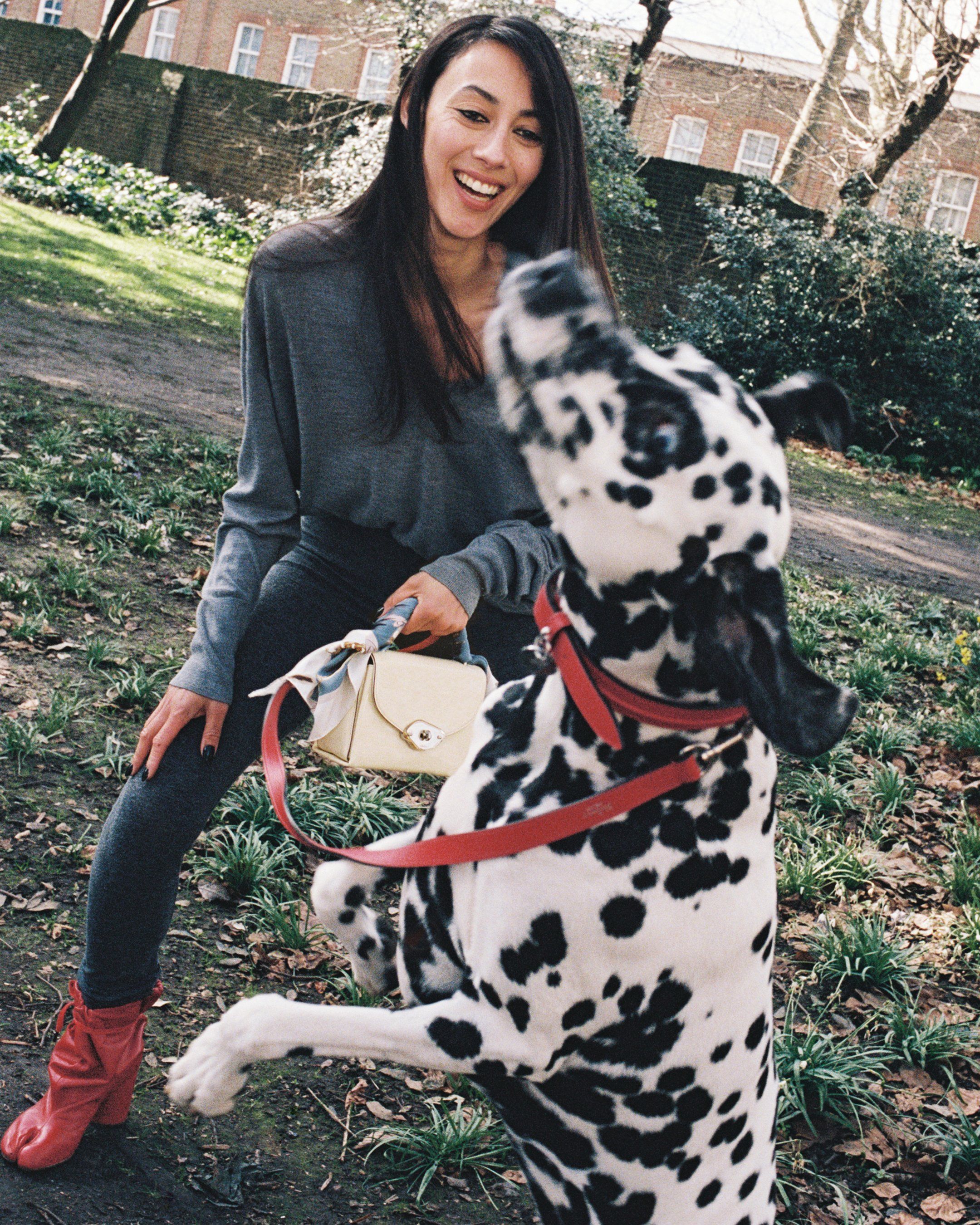 Model playing with a dog and holding a Mulberry Lana bag in pale yellow patent leather