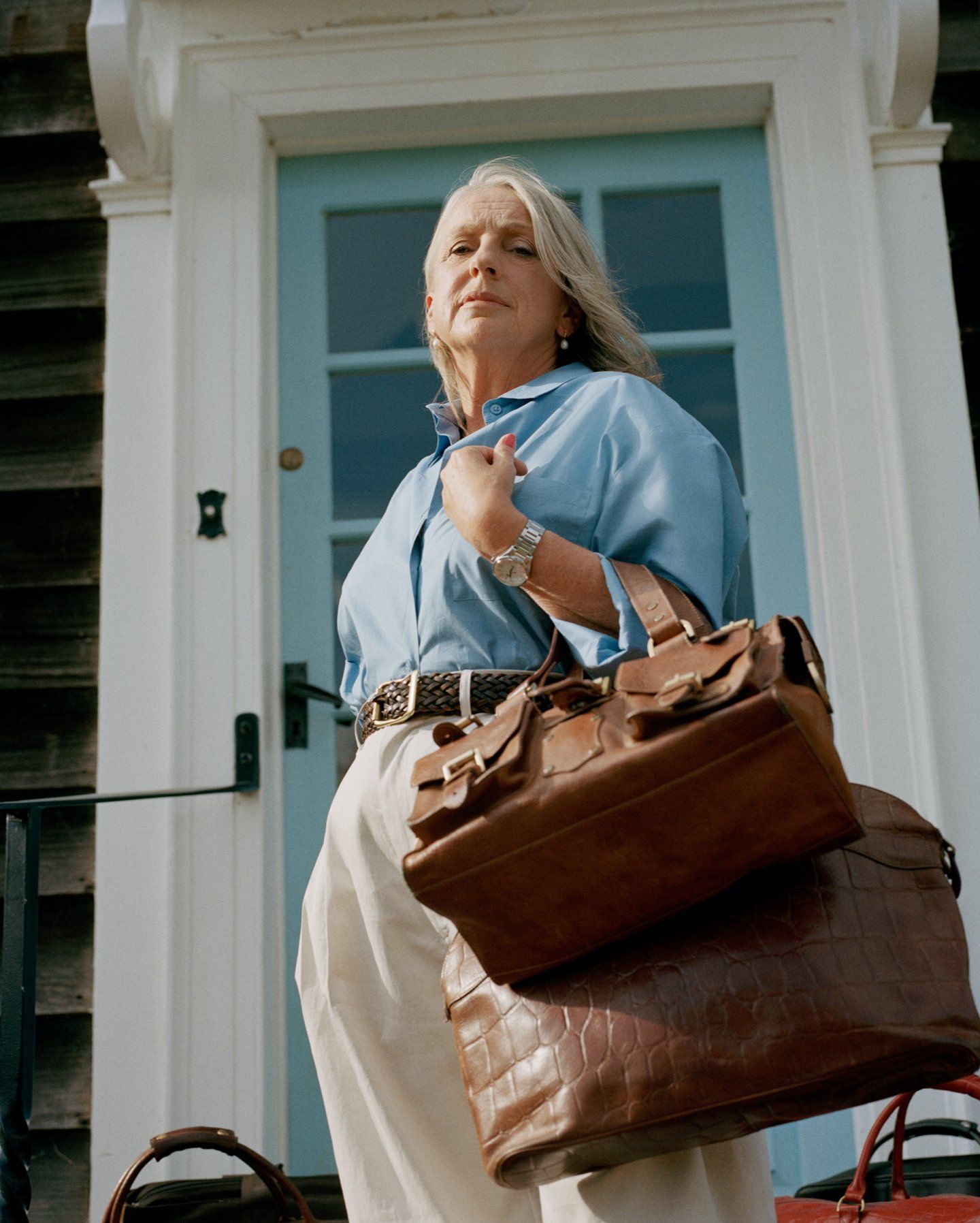 Woman standing outside her front door holding two brown Mulberry bags