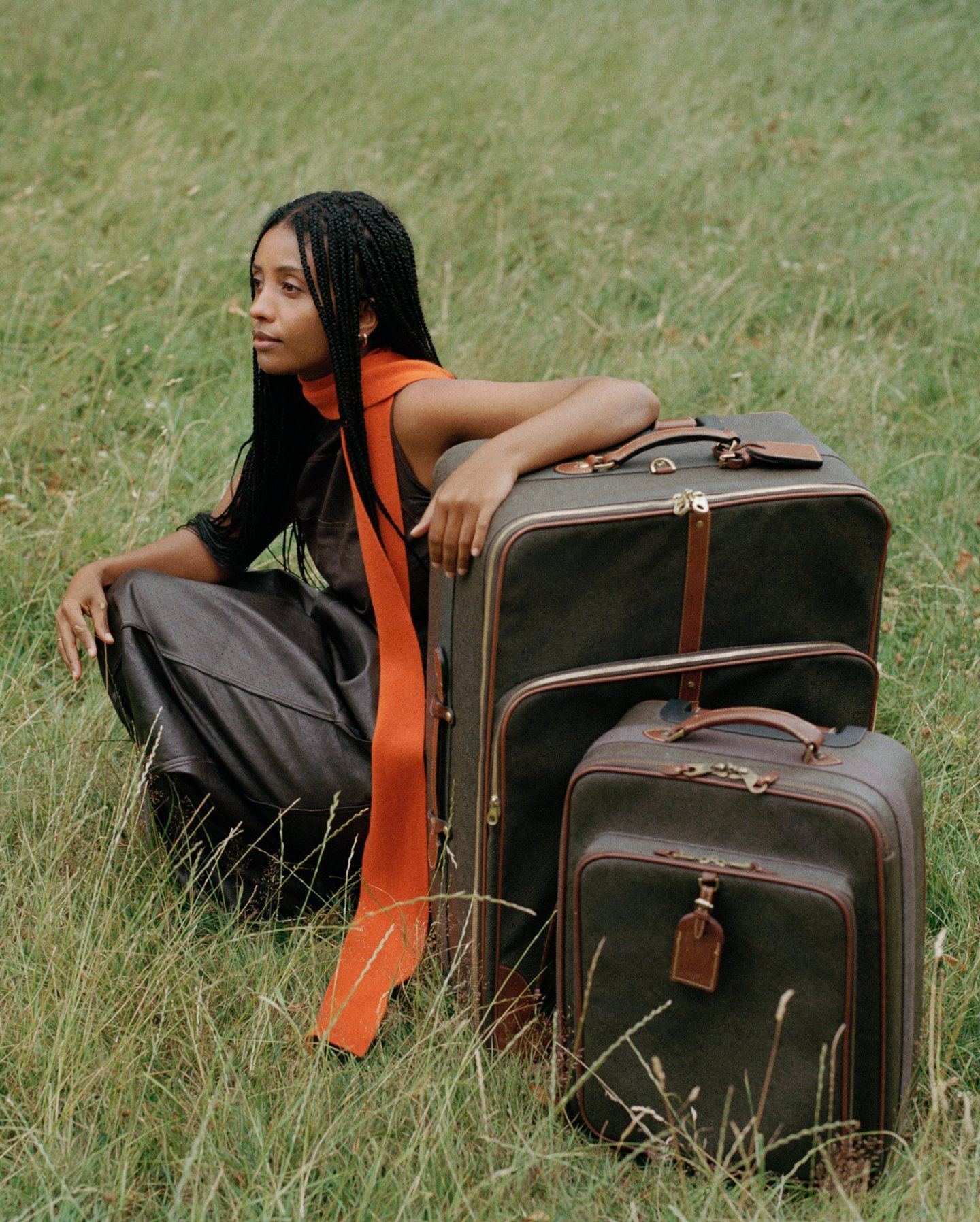 Woman sitting on the grass with two brown Mulberry suitcases