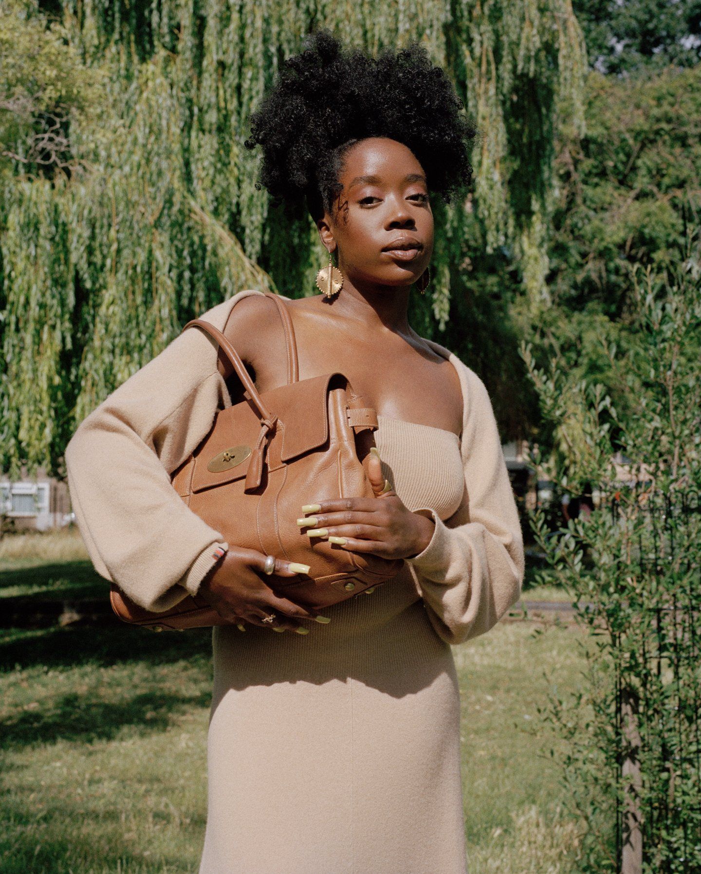 Woman in a beige dress holding a brown Mulberry Bayswater bag