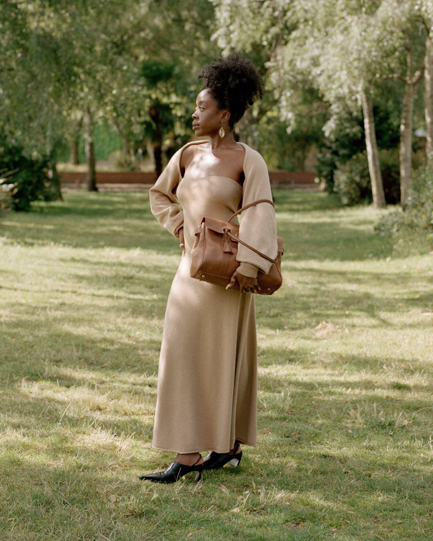 Woman in a beige dress standing outside and holding a brown Mulberry Bayswater bag