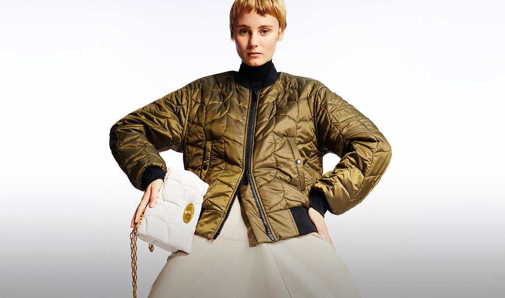 Model wearing a Softie jacket and holding a Softie bag in white