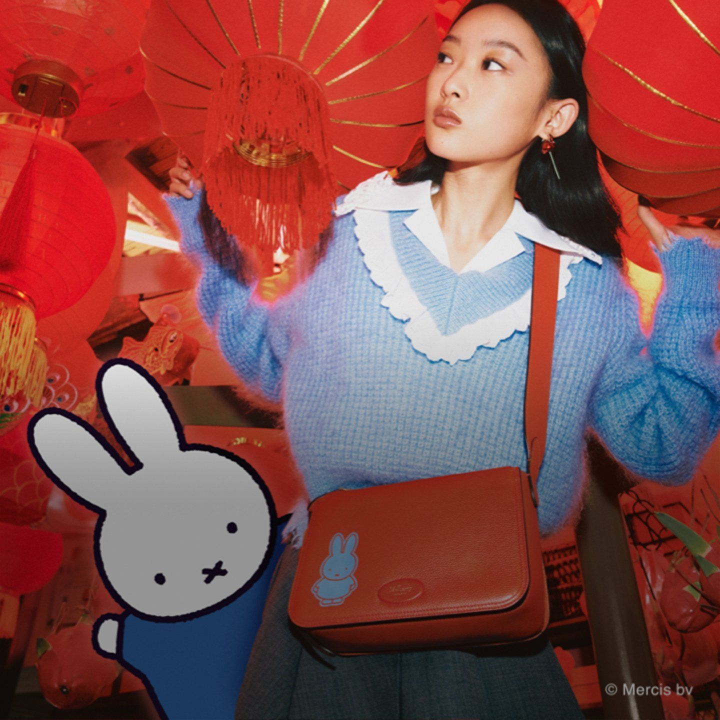 Model trägt eine Billie-Tasche von Mulberry x Miffy in Korallenorange mit blauem Miffy-Aufdruck