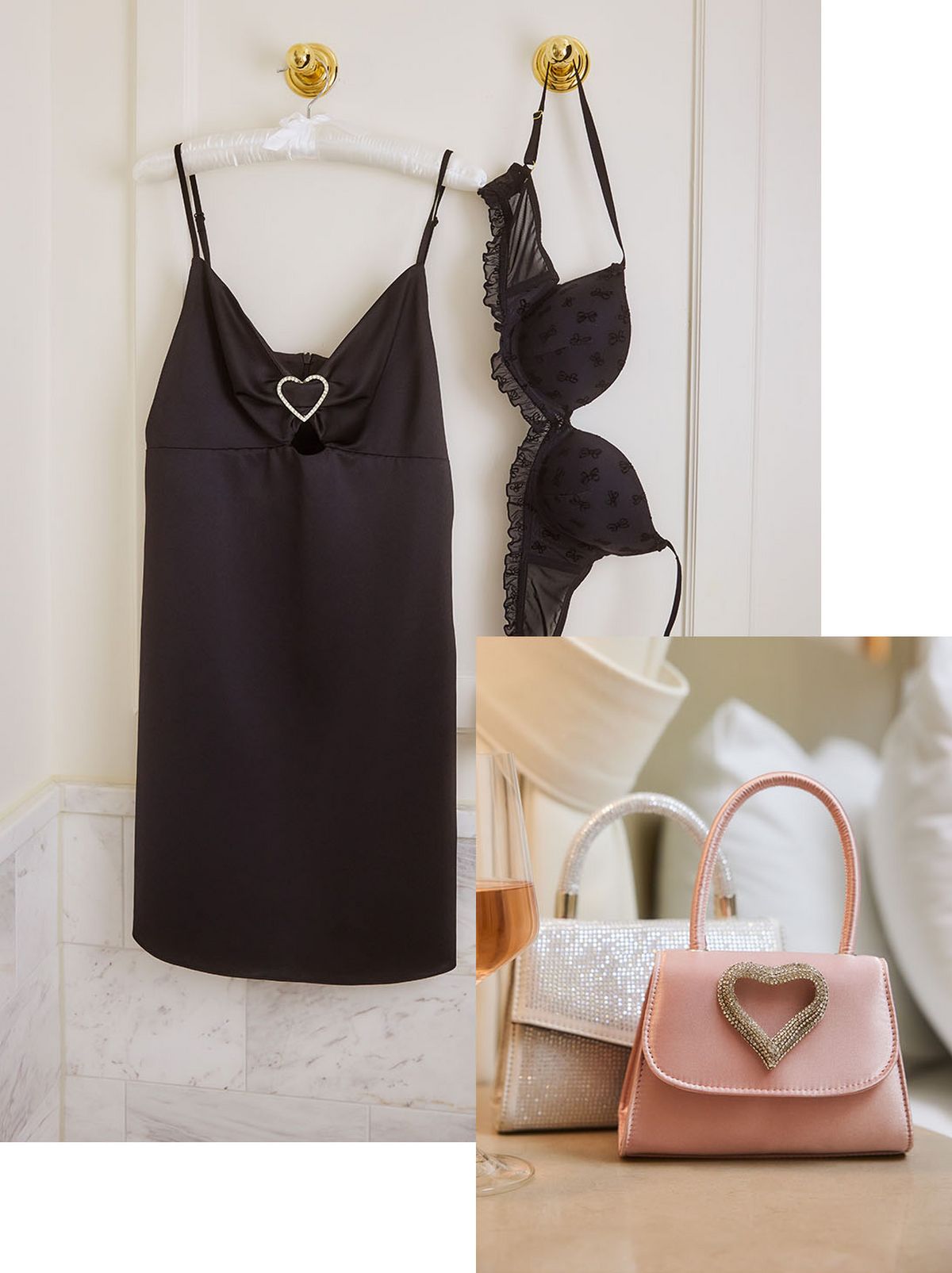 2 handbags with heart designs on the front are on a bedside table with a glass of wine next to them. A black lace bra and lace nightie are hung on a white wall 