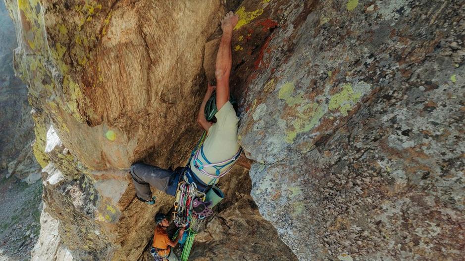 A single climber going up a wall with equipment.