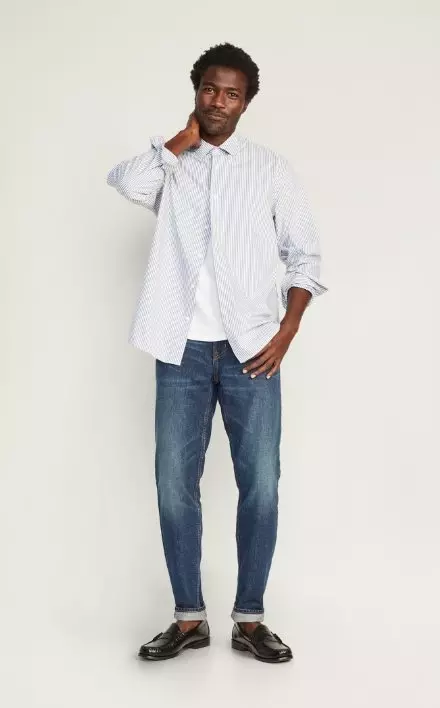 A male model wears Athletic Taper style jeans & a light colored long sleeve button-up shirt