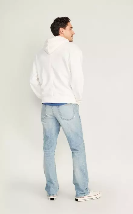 A male model wears Boot-Cut style jeans and a white colored logo hoodie