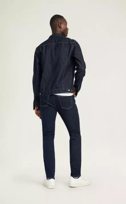 A male model wears Skinny style denim with a dark denin jacket
