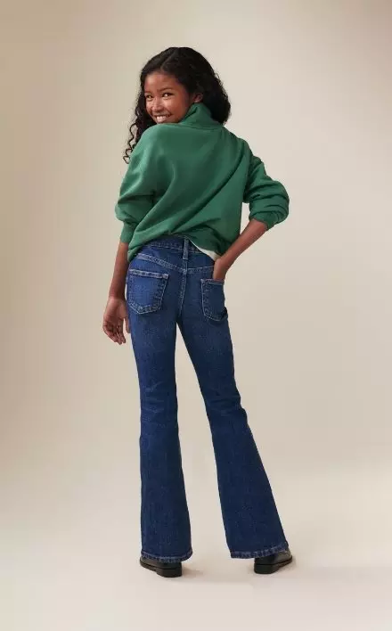 A model wearing dark washed built-in tough high waisted flare jean and a sweatshirt.