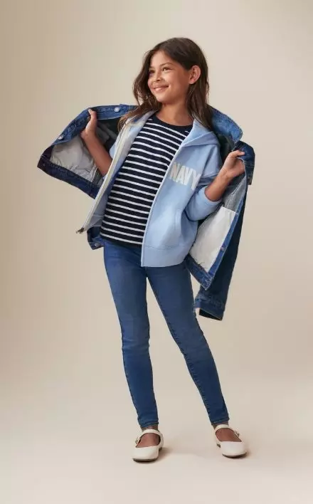 A young model wearing high waisted rockstar stretch jegging and striped top and blue hoodie.