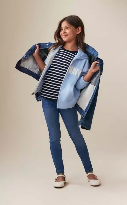 Une jeune fille porte un jegging Rockstar extensible à taille haute, un haut à rayures et un chandail à capuchon bleu.