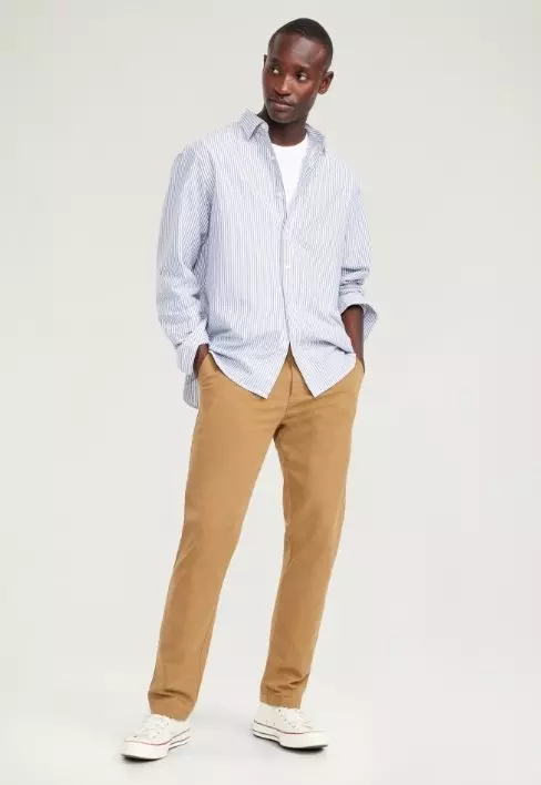 A male model wears light colored chino style slim pants.