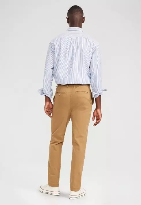 A male model wears light colored chino style slim pants.