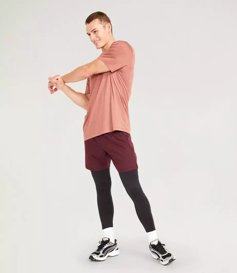 A male model wears dark base layer legging with his maroon activewear outfit.