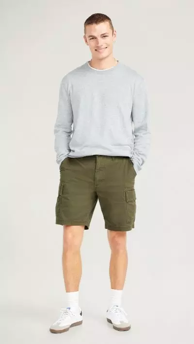 A male model wears a pair of dark green Lived-In Cargo Shorts -- 10-inch inseam