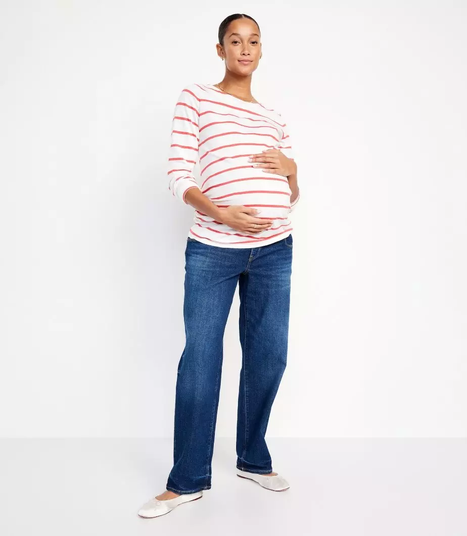 A pregnant model wearing a maternity striped top and wide-leg jeans.